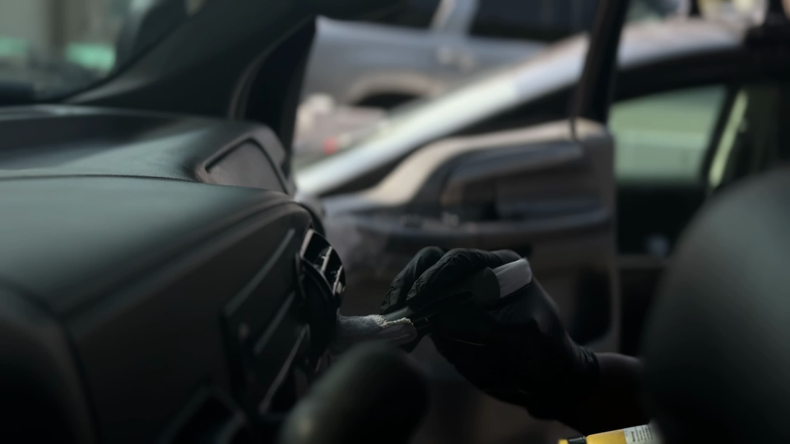A detailer working the vents of a dashboard with a soft brush