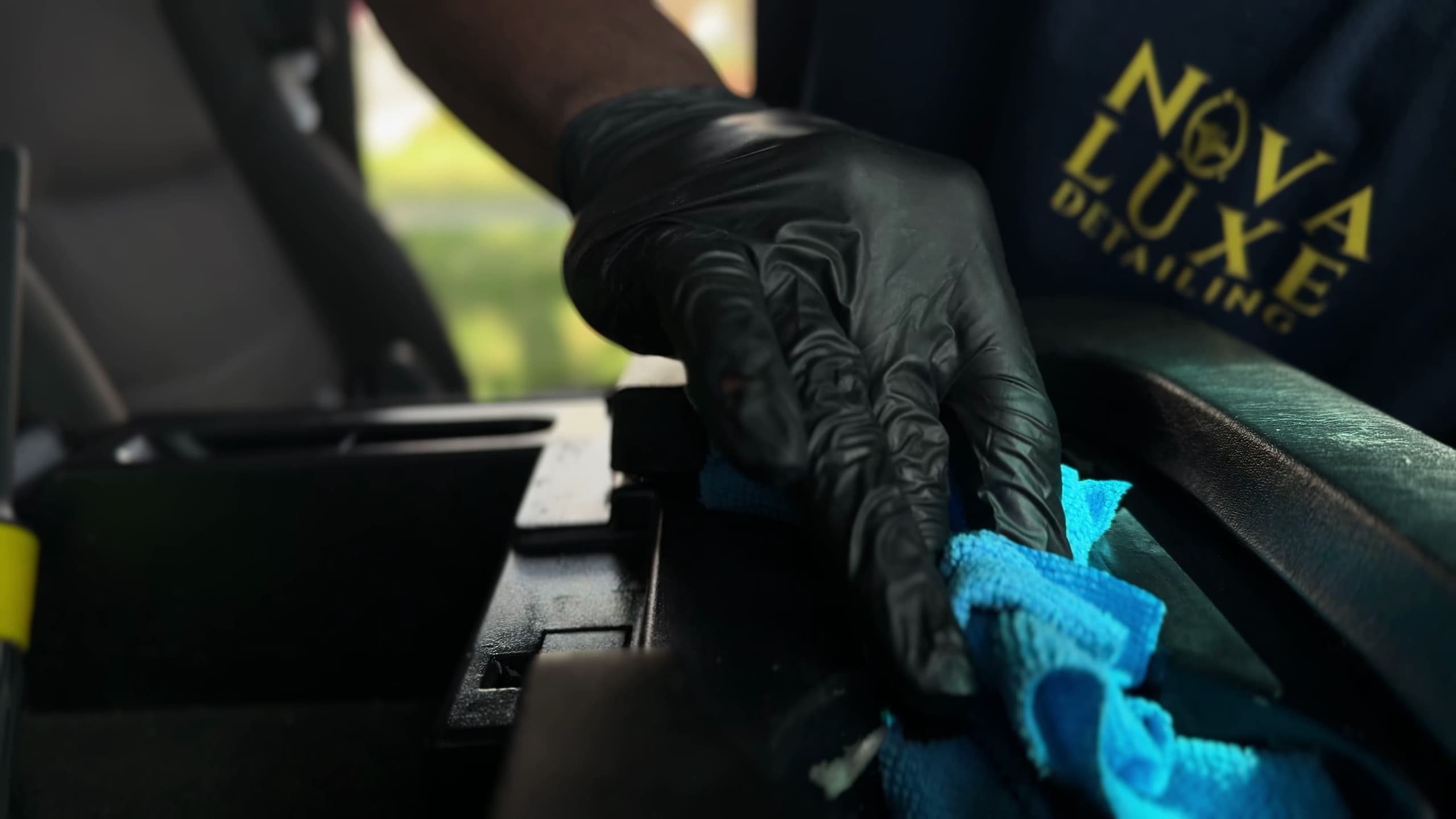A gloved hand steam-cleaning the seams of a dashboard